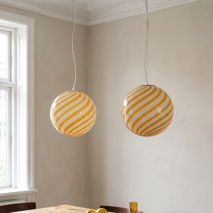 Dining table pendant light in a pair above a solid oak table – yellow swirl BO-HA Kaja globes.