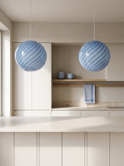Kitchen island pendant light in a pair above a travertine island – blue swirl BO-HA Kaja globes.
