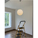 Round glass pendant light hanging in a bright empty room, the white BO-HA Kaja swirl globe.