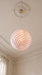 Retro pendant light seen from below against an ornate plaster ceiling rose – pink BO-HA Kaja globe.