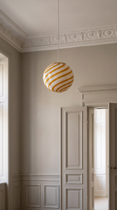 Yellow pendant light in a panelled hallway with stucco cornice – the amber swirl BO-HA Kaja globe.