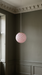 Pink pendant light against deep olive dining room walls with an ornate cornice – BO-HA Kaja globe.