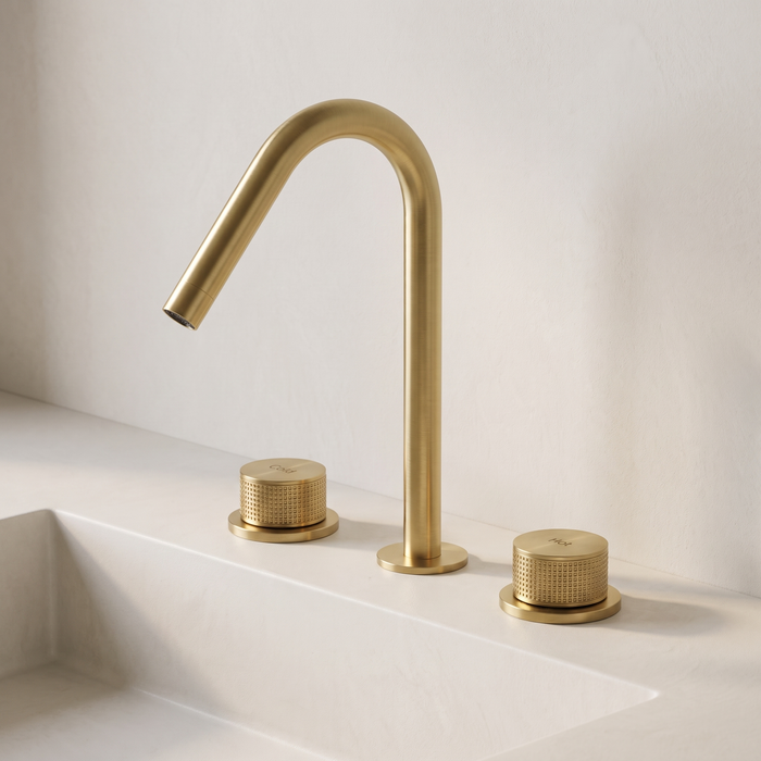 Kilde widespread bathroom faucet in brushed gold – knurled dual handles on a white stone basin