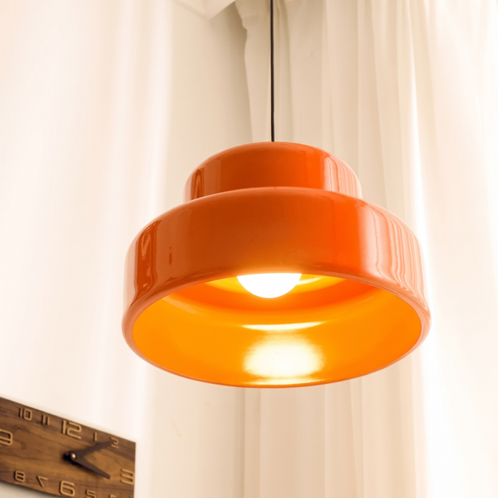 Close-up of the lit Sunna pendant, warm 2700K glow reflecting inside the orange iron shade against a white curtain