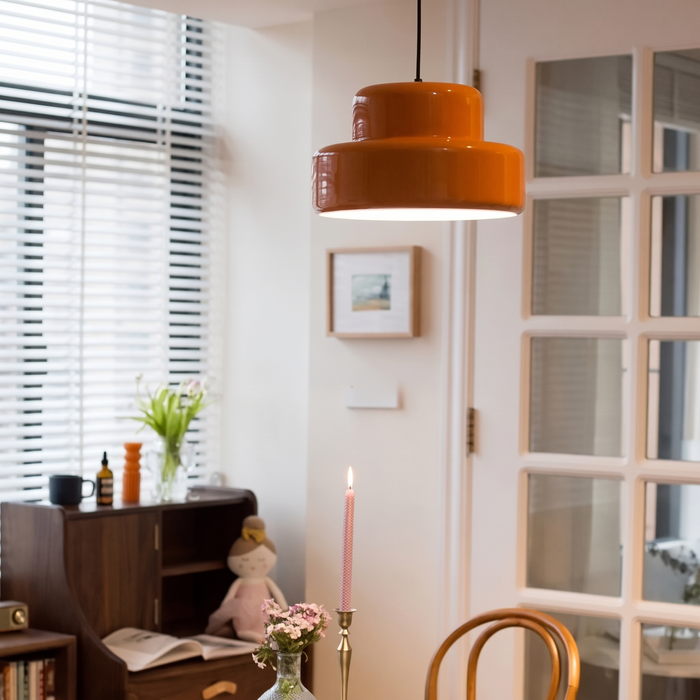 Sunna pendant light glowing over a dining corner with glazed French doors, a dark sideboard and framed art on a white wall