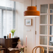 Sunna pendant light glowing over a dining corner with glazed French doors, a dark sideboard and framed art on a white wall